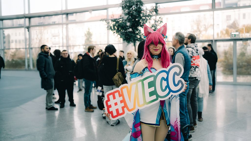 Eine verkleidete Frau hält ein Schild mit dem Schriftzug #VIECC
