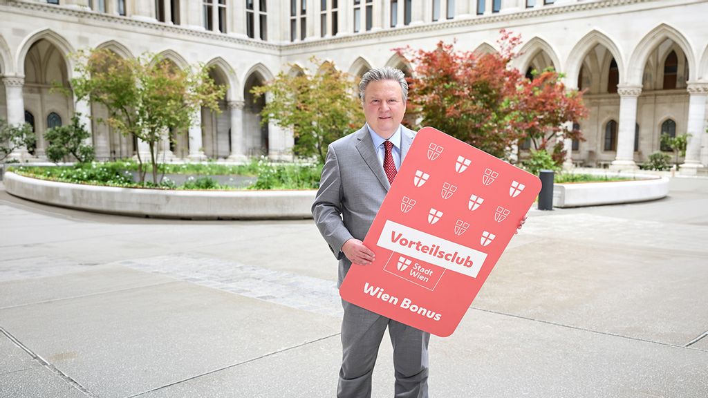 Bürgermeister Michael Ludwig steht mit einer Wien Bonus Karte im Arkadenhof des Wiener Rathauses