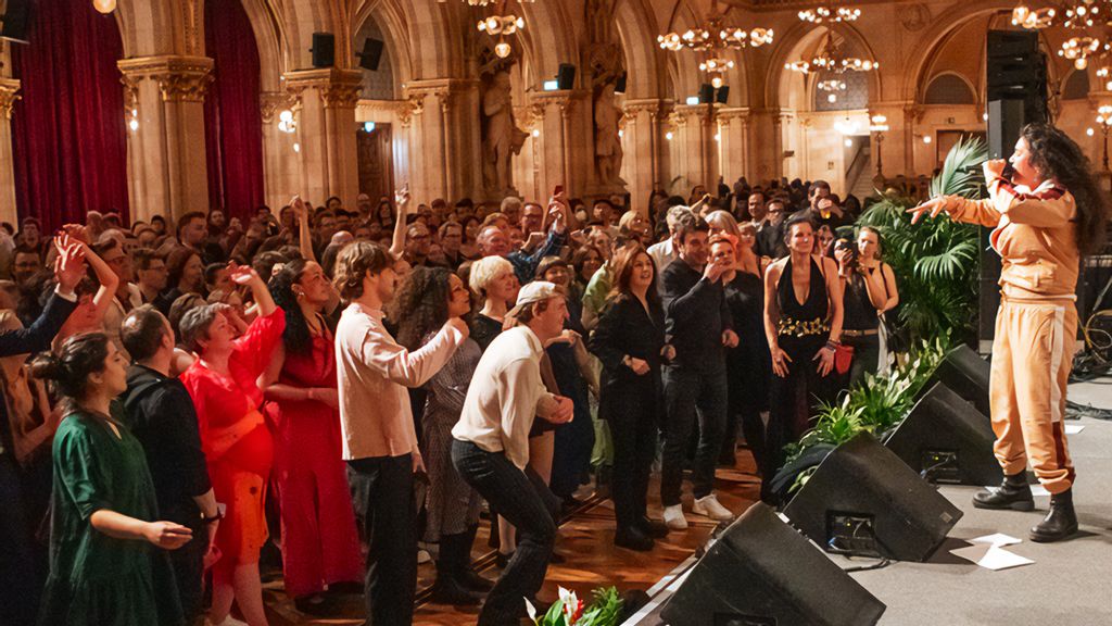 Gäste des Flüchtlingsballs stehen vor einer Bühne auf der eine Sängerin steht