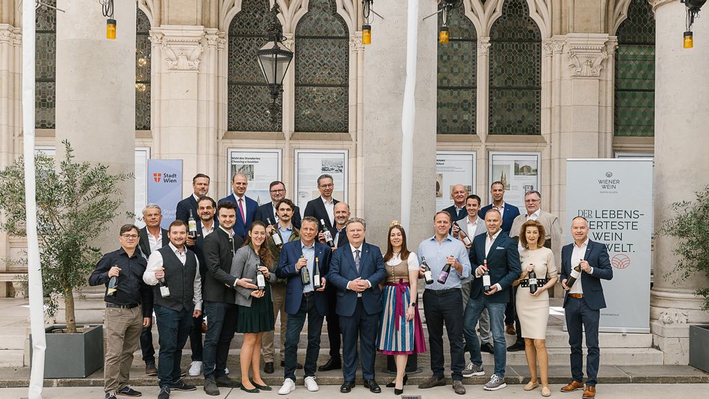 Ein Gruppenfoto mit dem Bürgermeister und Personen, die eine Weinflasche in der Hand halten