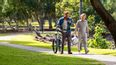 Zwei Männer gehen nebeneinander und einer schiebt ein Fahrrad