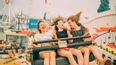 Drei Mädchen sitzen nebeneinander in einem Fahrgeschäft des Wiener Praters