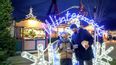 Ein Pärchen steht vor einem beleuchteten Schild beim Wintermarkt am Riesenradplatz